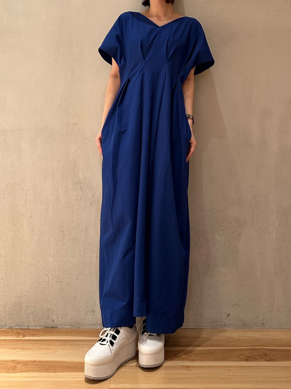 ブルー系のワンピース、ホワイト系のスニーカー、ブラック系のキャップを着用したレディースの春コーディネートの3枚目の写真