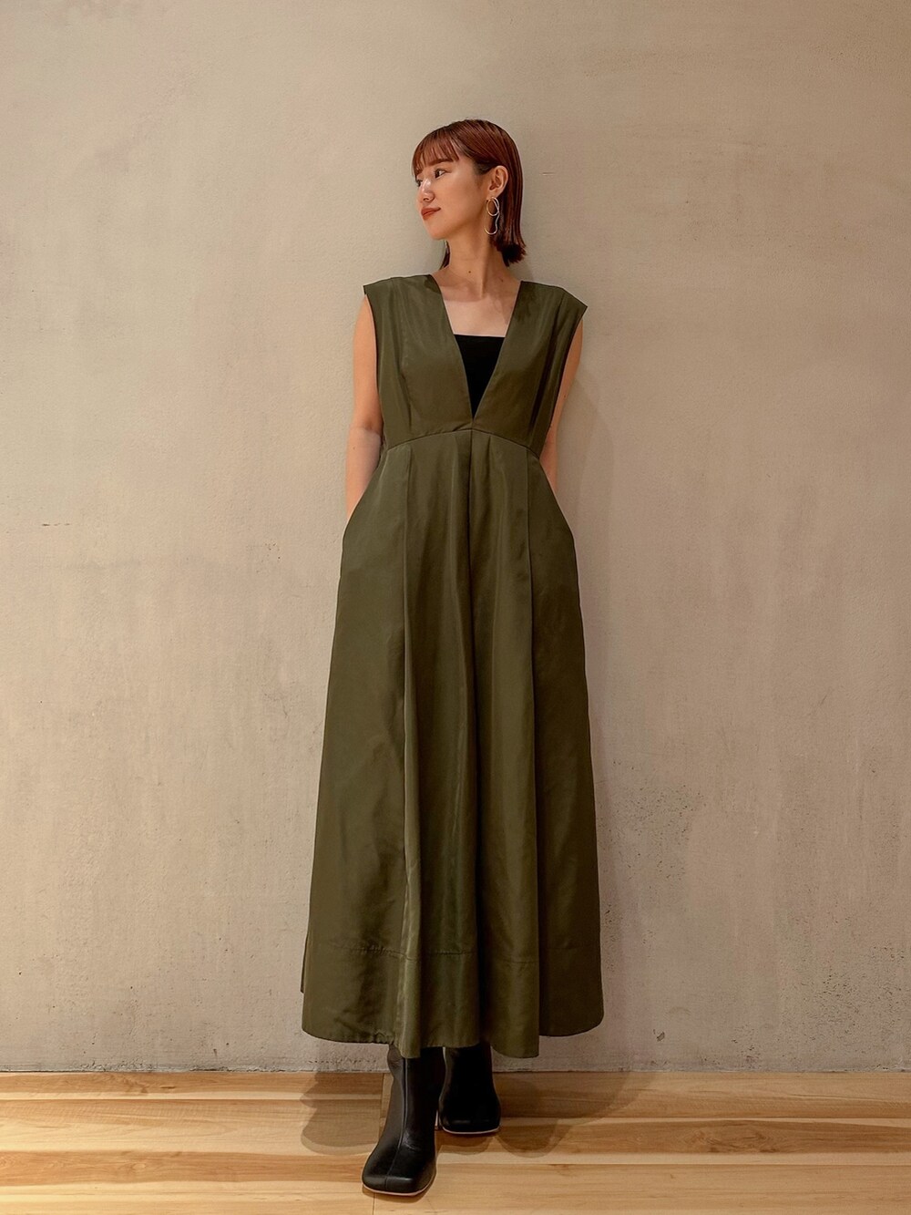 グリーン系のジャンパースカート、ブラック系のブーツを着用したレディースの夏コーディネートの3枚目の写真