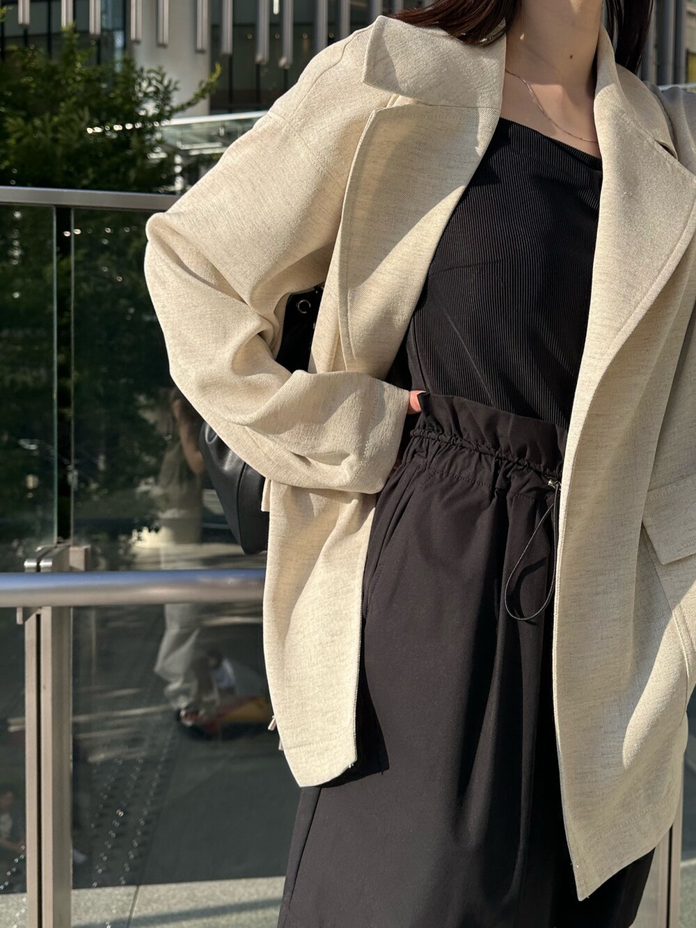 ブラック系のキャミソール、ベージュ系のテーラードジャケット、ブラック系のショルダーバッグを着用したレディースの春コーディネートの6枚目の写真