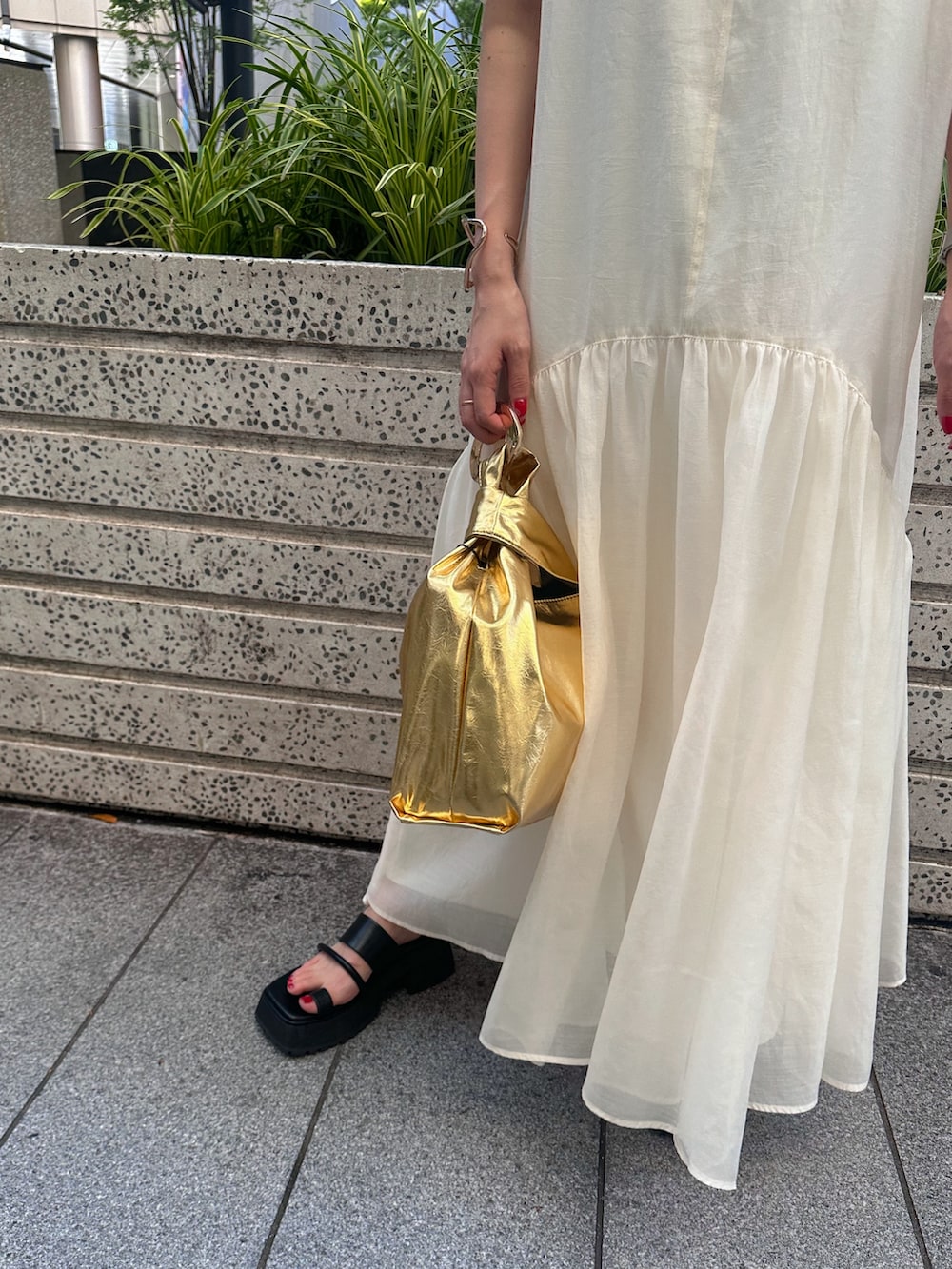 ブラック系のキャミソール、ゴールド系のハンドバッグ、ブラック系のサンダルを着用したレディースの夏コーディネートの7枚目の写真