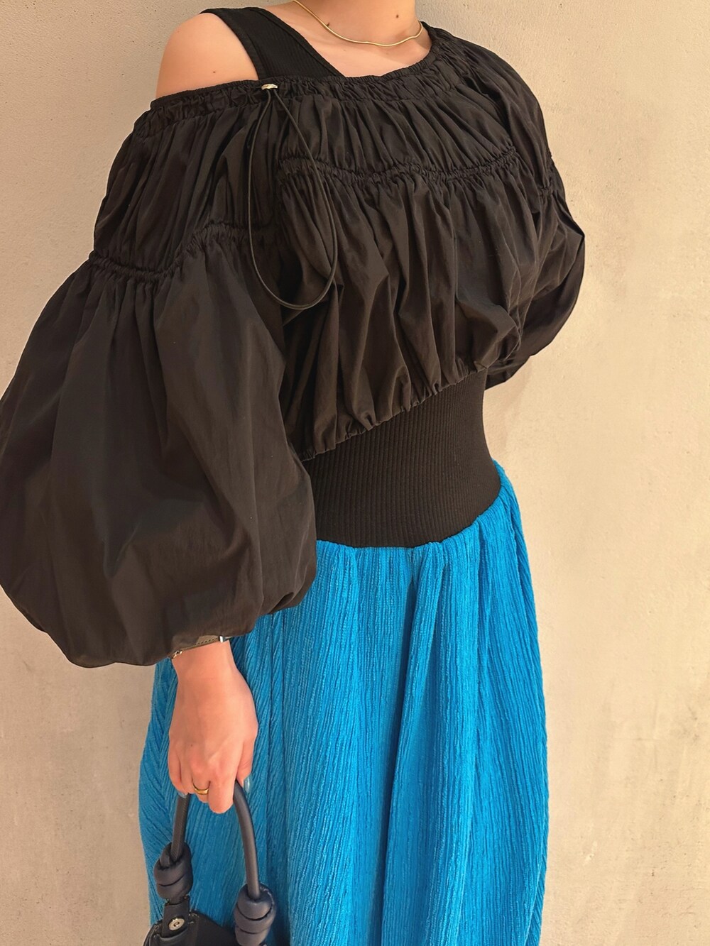 ベージュ系のハンドバッグ、ブルー系のワンピース、ホワイト系のスニーカーを着用したレディースの冬コーディネートの3枚目の写真