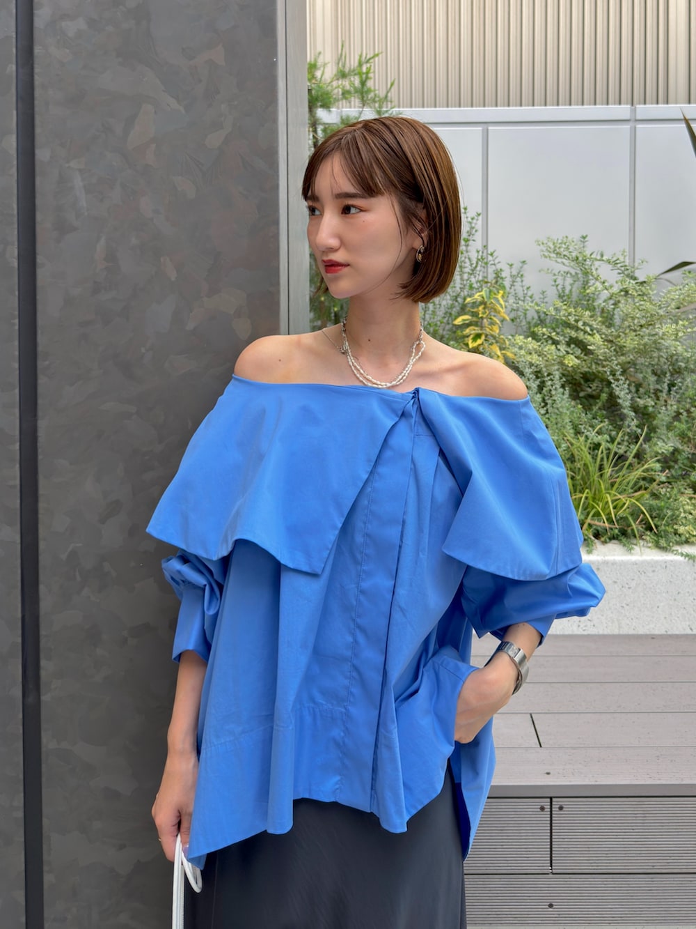 ブルー系のシャツ/ブラウス、グレー系のスカート、ゴールド系のネックレスを着用したレディースの夏コーディネートの3枚目の写真