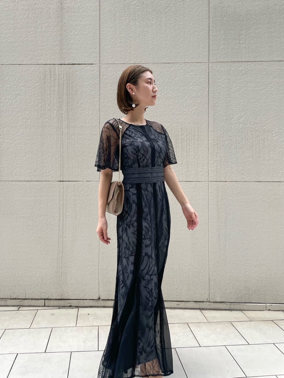 ゴールド系のパンプス、ゴールド系のクラッチバッグ、ブラック系のドレスを着用したレディースの春コーディネートの6枚目の写真
