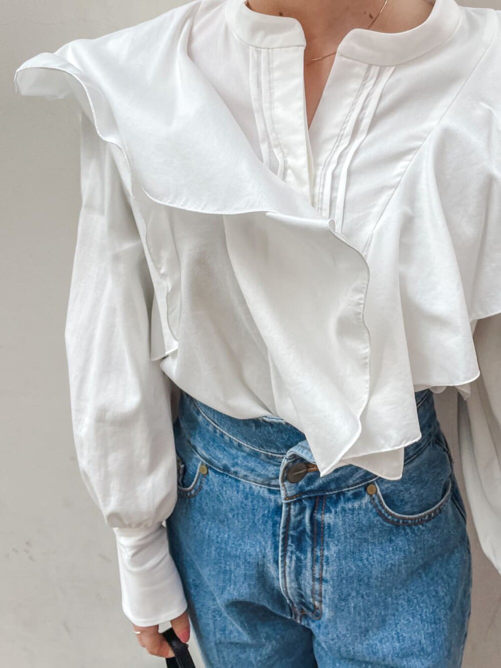 ベージュ系のパンプス、ブラック系のハンドバッグ、ブルー系のデニムパンツを着用したレディースの冬コーディネートの6枚目の写真