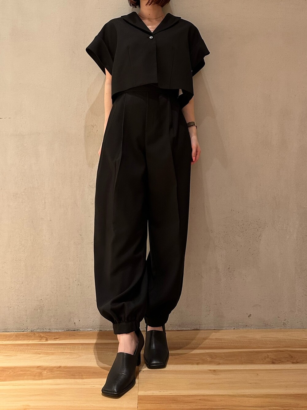 ブラック系のスラックス、ブラック系のニット/セーター、ブラック系のテーラードジャケットを着用したレディースの春コーディネートの2枚目の写真