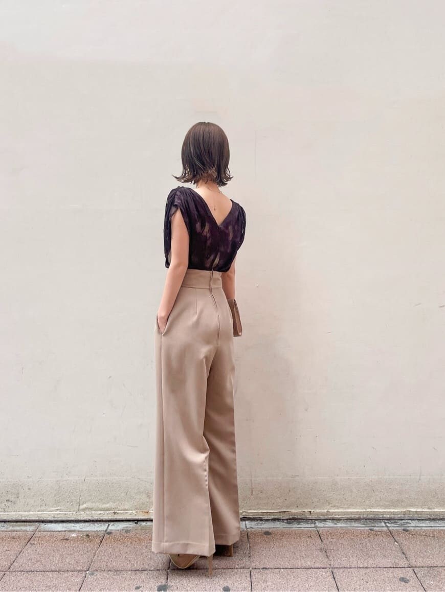 ゴールド系のクラッチバッグ、ベージュ系のパンツドレス、ゴールド系のパンプスを着用したレディースの春コーディネートの7枚目の写真