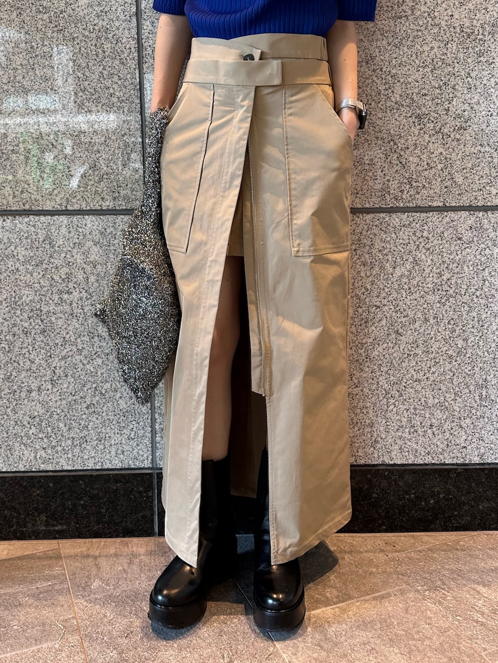 ブルー系のニット/セーター、ブラック系のノーカラージャケット、ベージュ系のスカートを着用したレディースの秋コーディネートの9枚目の写真