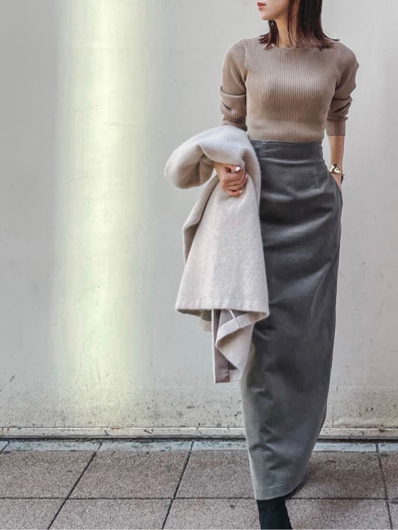 ブラック系のブーツ、ベージュ系のニット/セーター、グレー系のスカートを着用したレディースの秋コーディネートの2枚目の写真