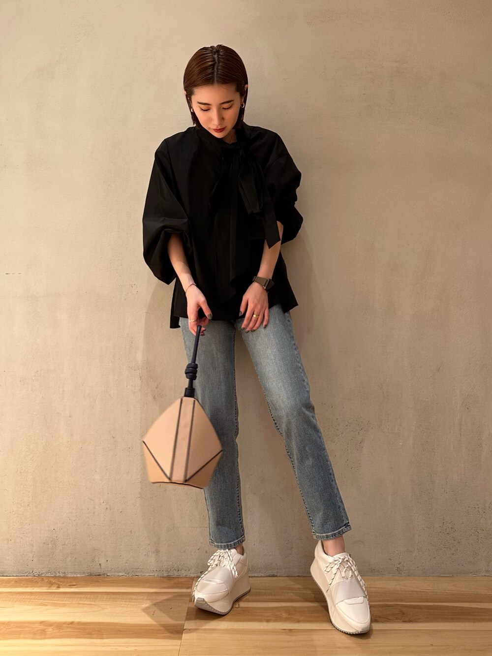 ホワイト系のスニーカー、ベージュ系のハンドバッグ、ブルー系のデニムパンツを着用したレディースの春コーディネートの3枚目の写真