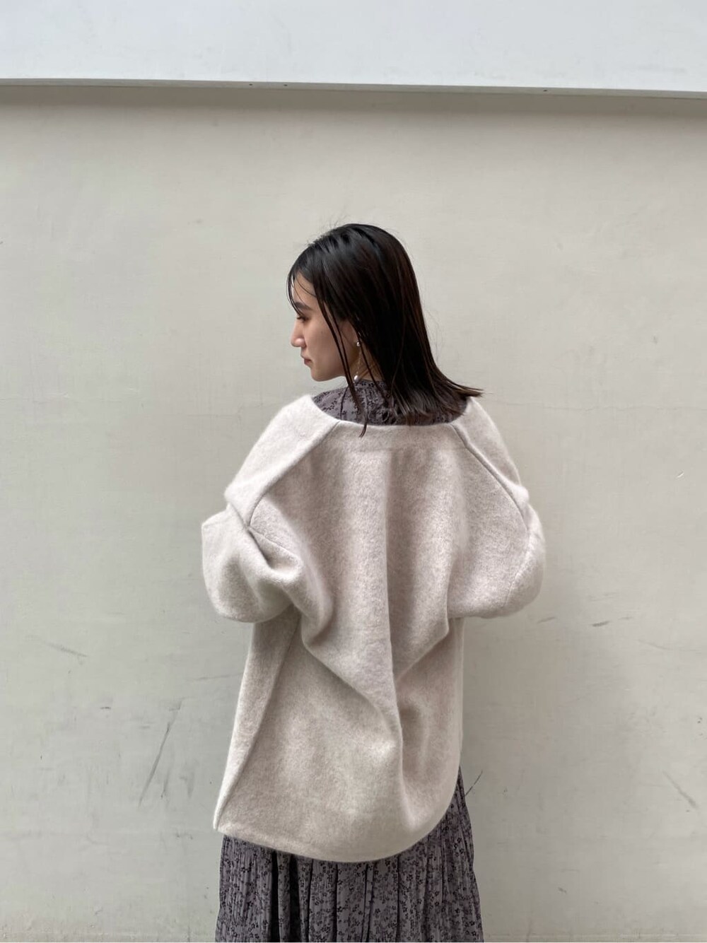 グレー系のワンピース、ホワイト系のカーディガン/ボレロ、ホワイト系のピアス（両耳用）を着用したレディースの秋コーディネートの4枚目の写真