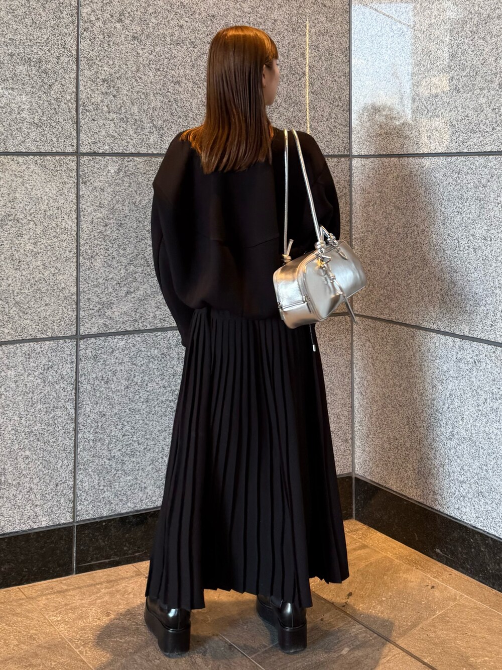 ブラック系のスウェット、シルバー系のボストンバッグ、ブラック系のワンピースを着用したレディースの冬コーディネートの6枚目の写真