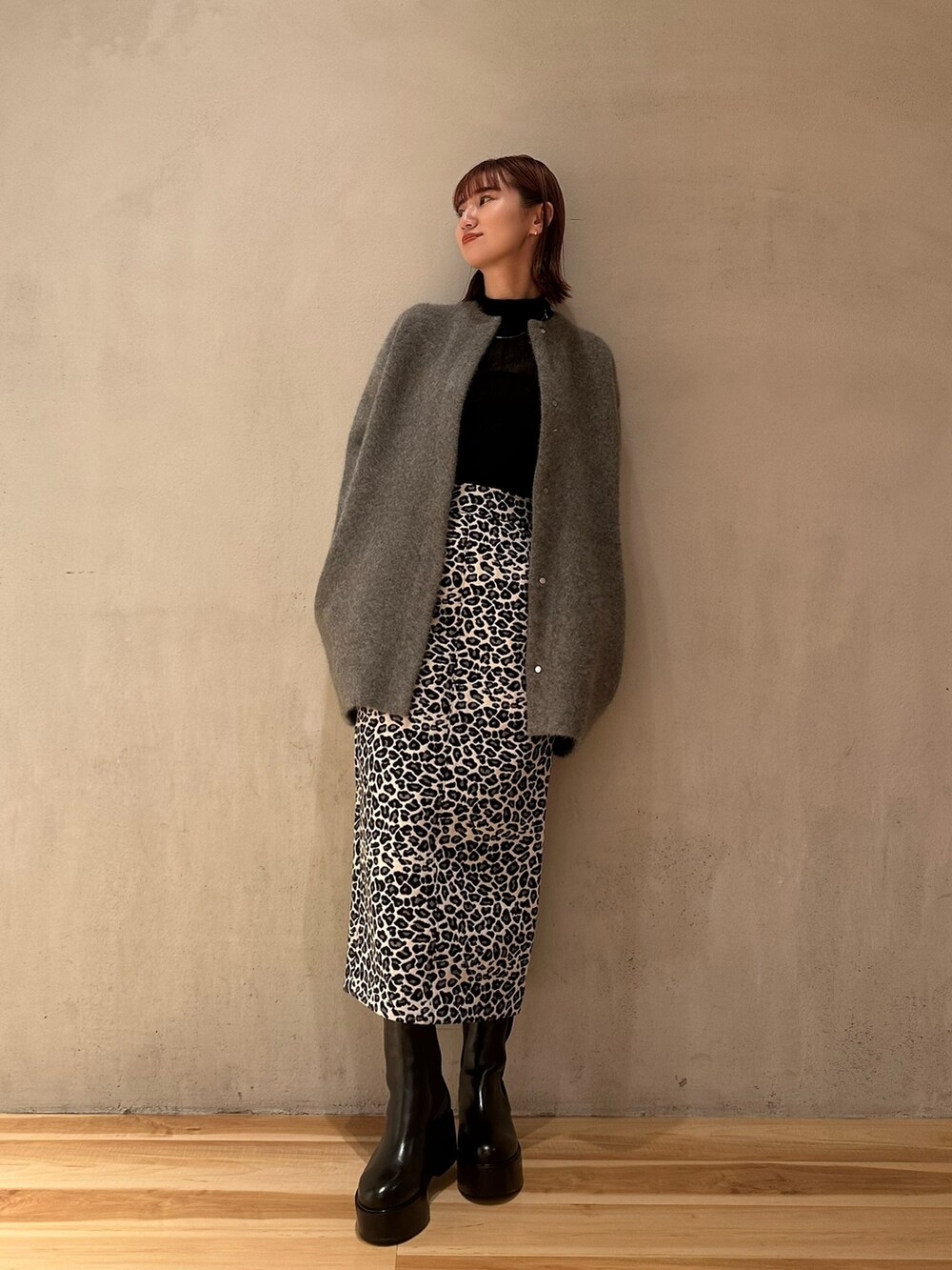 ブラック系のブーツ、ホワイト系のスカート、ブラック系のニット/セーターを着用したレディースの秋コーディネートの2枚目の写真