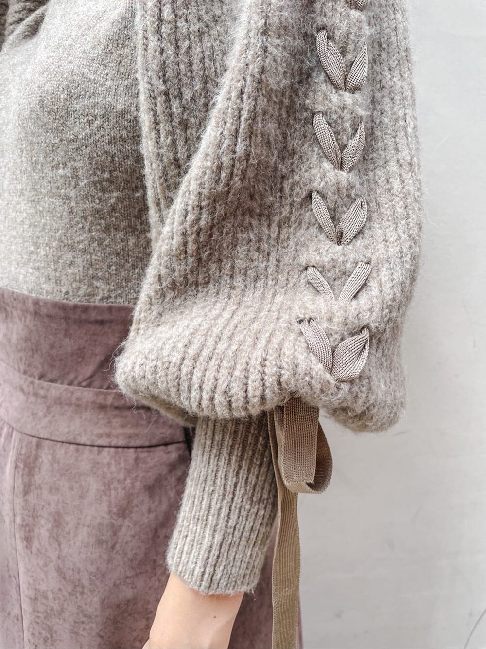 ブラック系のブーツ、ブラウン系のスカート、ベージュ系のニット/セーターを着用したレディースの秋コーディネートの3枚目の写真