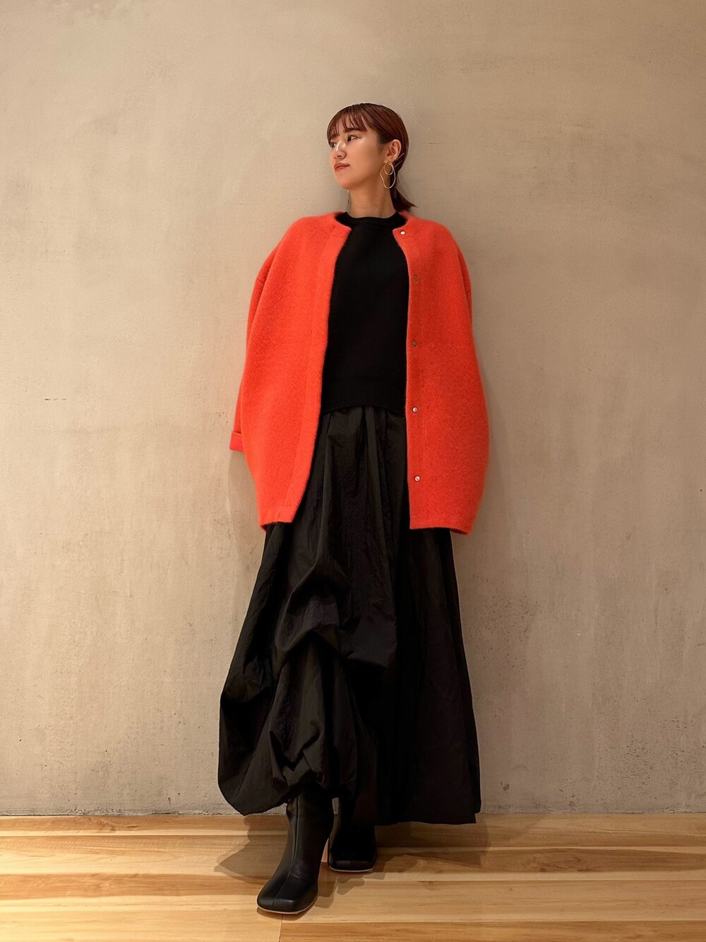 ブラック系のニット/セーター、ブラック系のブーツ、ピンク系のノーカラージャケットを着用したレディースの夏コーディネートの2枚目の写真