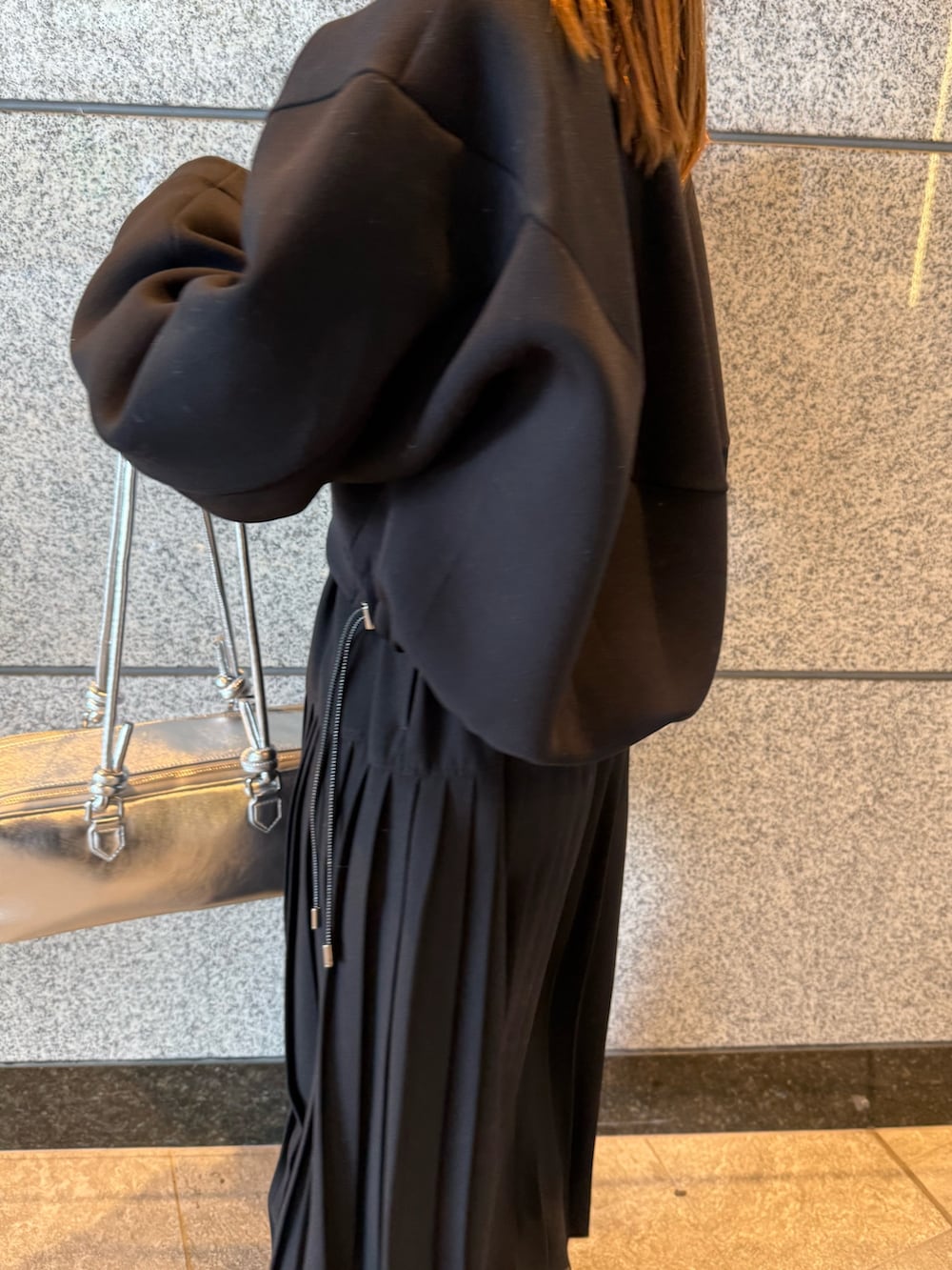 ブラック系のスウェット、シルバー系のボストンバッグ、ブラック系のワンピースを着用したレディースの冬コーディネートの8枚目の写真