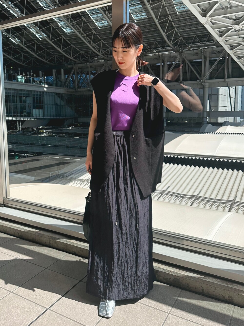 ブラック系のテーラードジャケット、ブルー系のスカート、シルバー系のパンプスを着用したレディースの春コーディネートの2枚目の写真