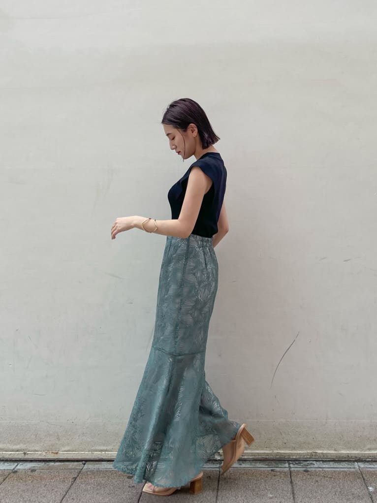 ブルー系のスカート、ベージュ系のサンダル、ブラック系のニット/セーターを着用したレディースの夏コーディネートの2枚目の写真