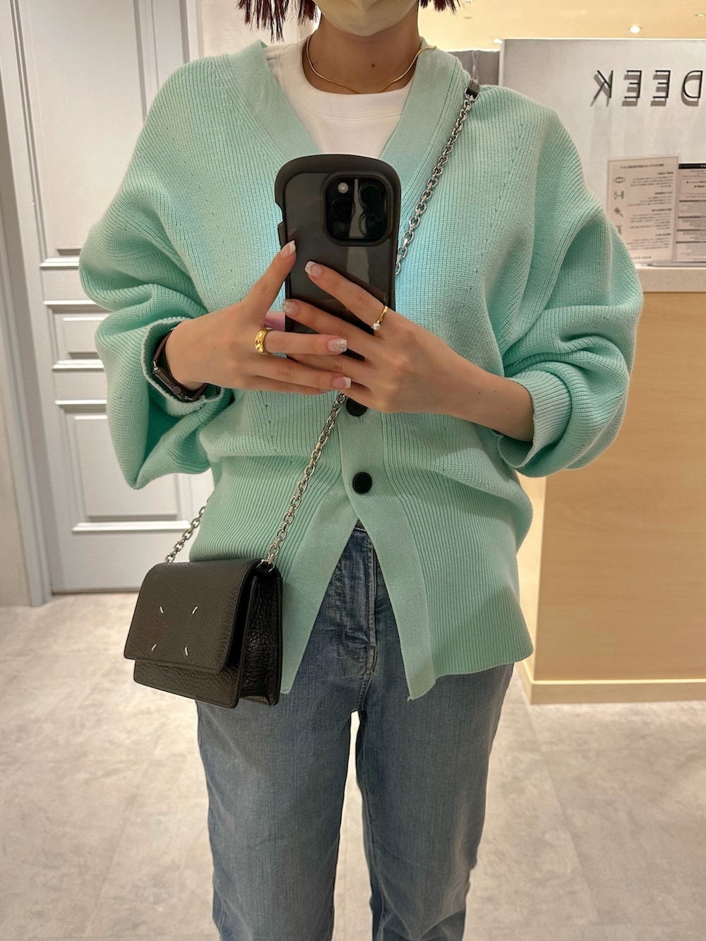 ブルー系のデニムパンツ、グリーン系のカーディガン/ボレロ、ホワイト系のTシャツ/カットソーを着用したレディースの冬コーディネートの4枚目の写真