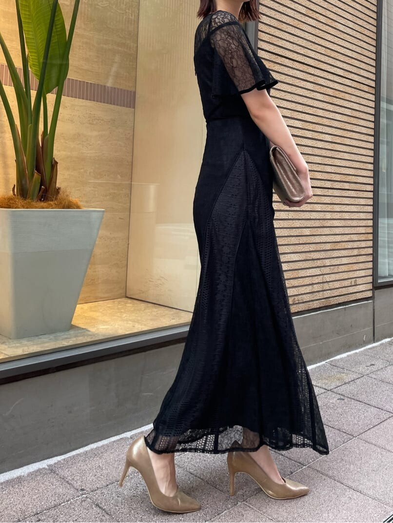 ゴールド系のパンプス、ゴールド系のクラッチバッグ、ブラック系のドレスを着用したレディースの夏コーディネートの5枚目の写真