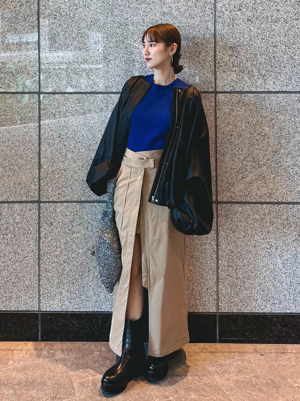 ブルー系のニット/セーター、ブラック系のノーカラージャケット、ベージュ系のスカートを着用したレディースの秋コーディネートの3枚目の写真