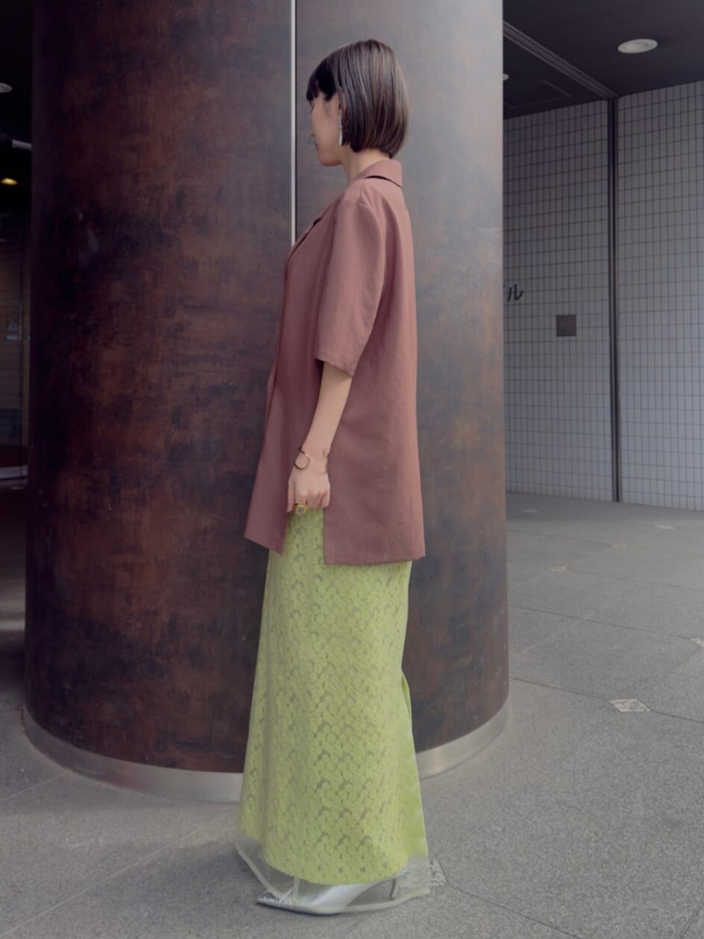 シルバー系のパンプス、ブラウン系のテーラードジャケット、グリーン系のスカートを着用したレディースの春コーディネートの2枚目の写真