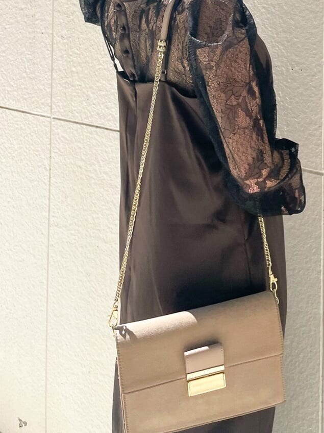 ブラック系のドレス、ベージュ系のパンプス、ベージュ系のクラッチバッグを着用したレディースの秋コーディネートの5枚目の写真