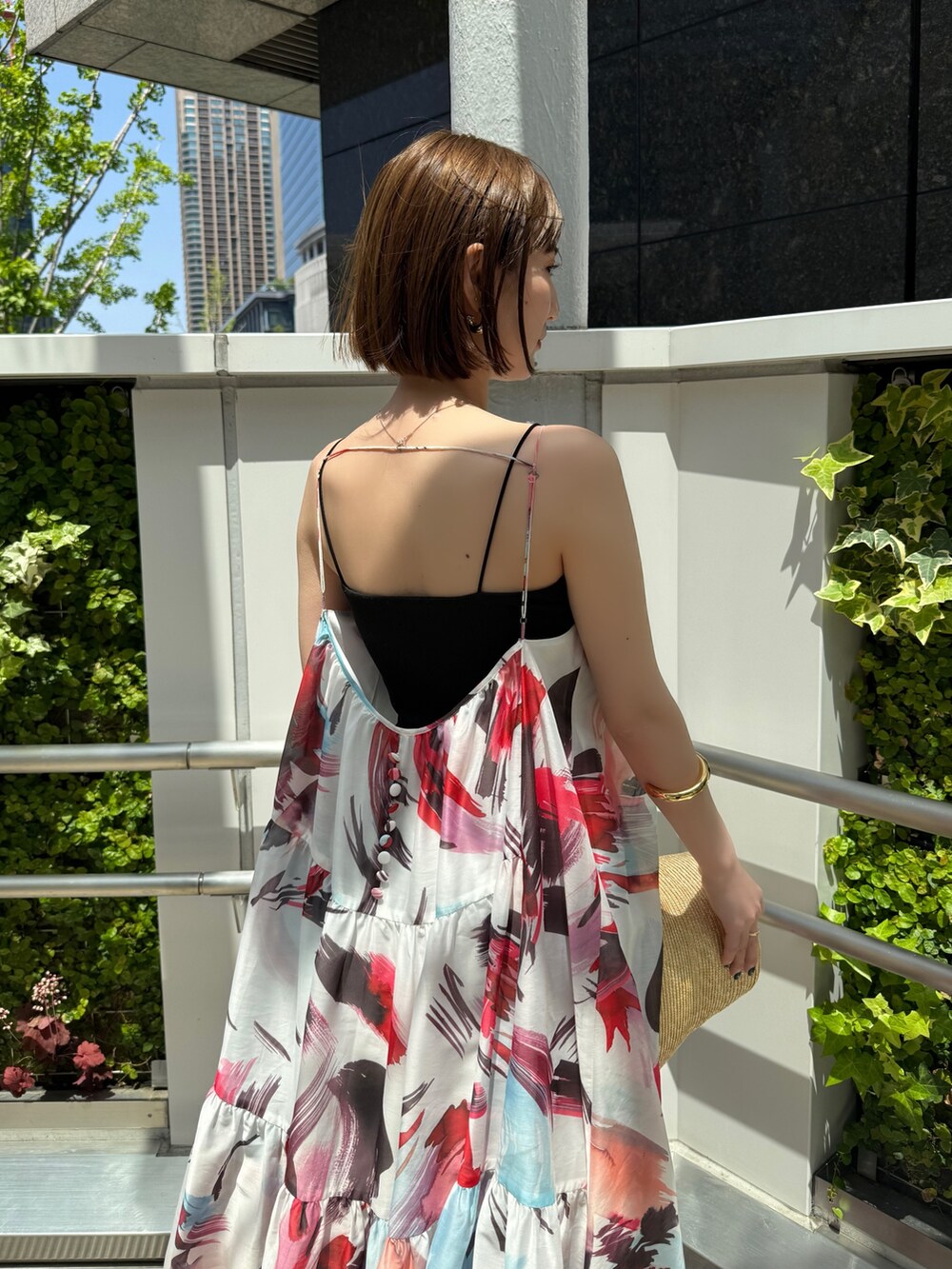 レッド系のワンピース、ブラック系のサンダル、ベージュ系のハットを着用したレディースの春コーディネートの6枚目の写真