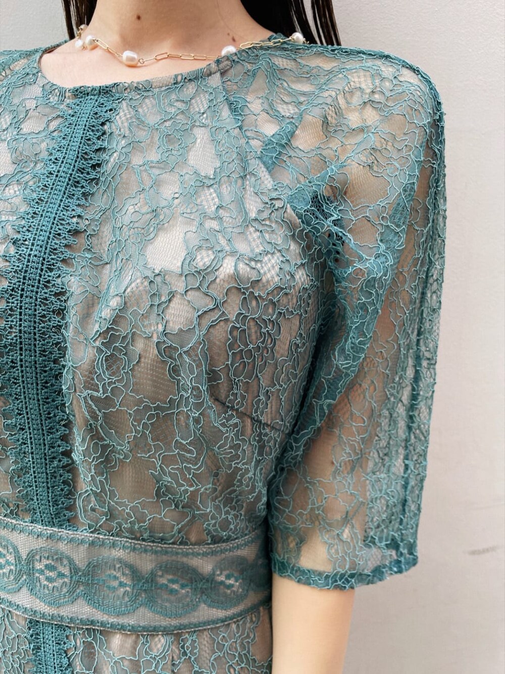 グリーン系のドレス、ベージュ系のパンプス、ブラウン系のクラッチバッグを着用したレディースの夏コーディネートの4枚目の写真