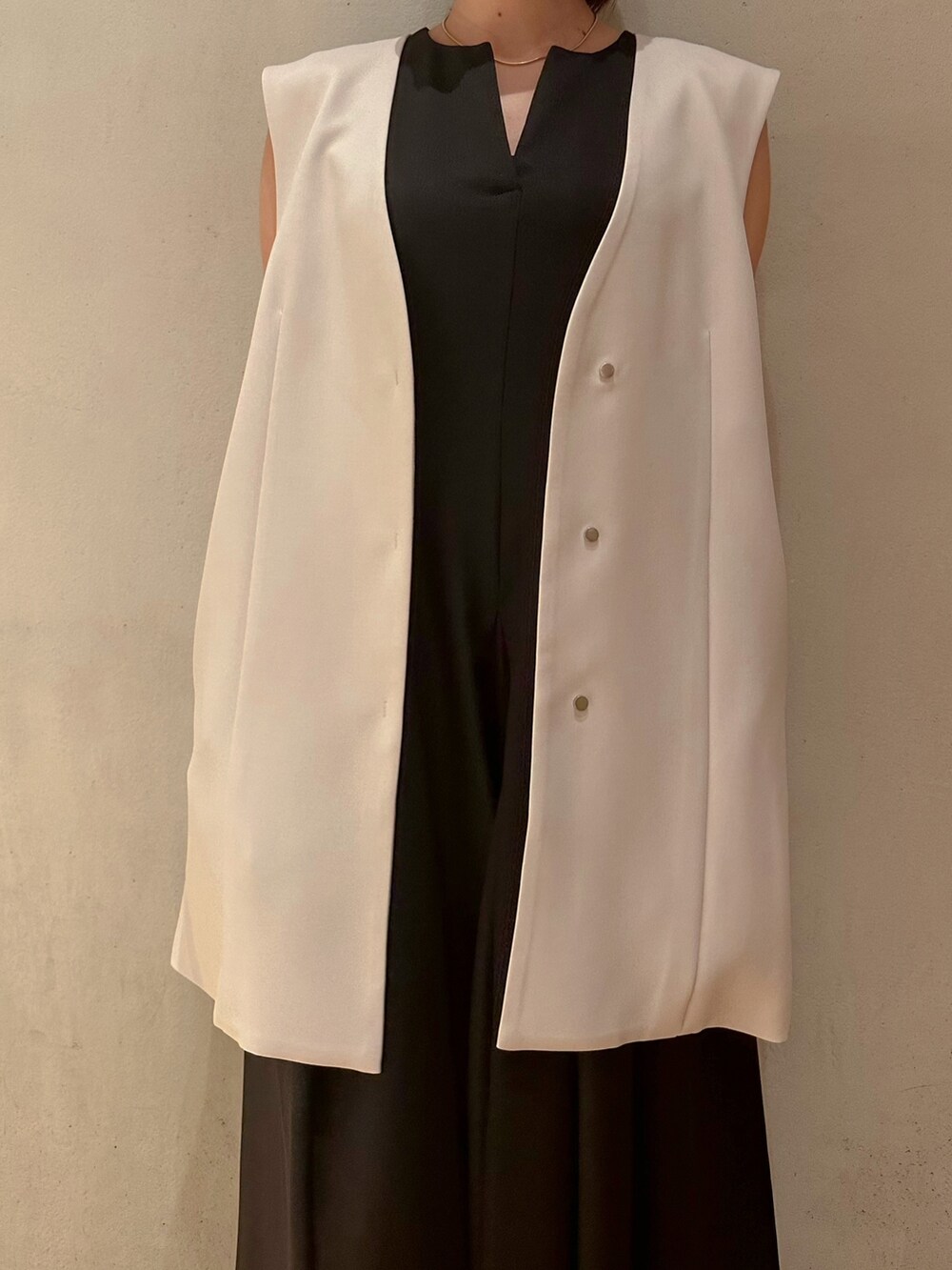 ベージュ系のテーラードジャケット、ブラック系のスニーカー、ブラック系のワンピースを着用したレディースの冬コーディネートの4枚目の写真