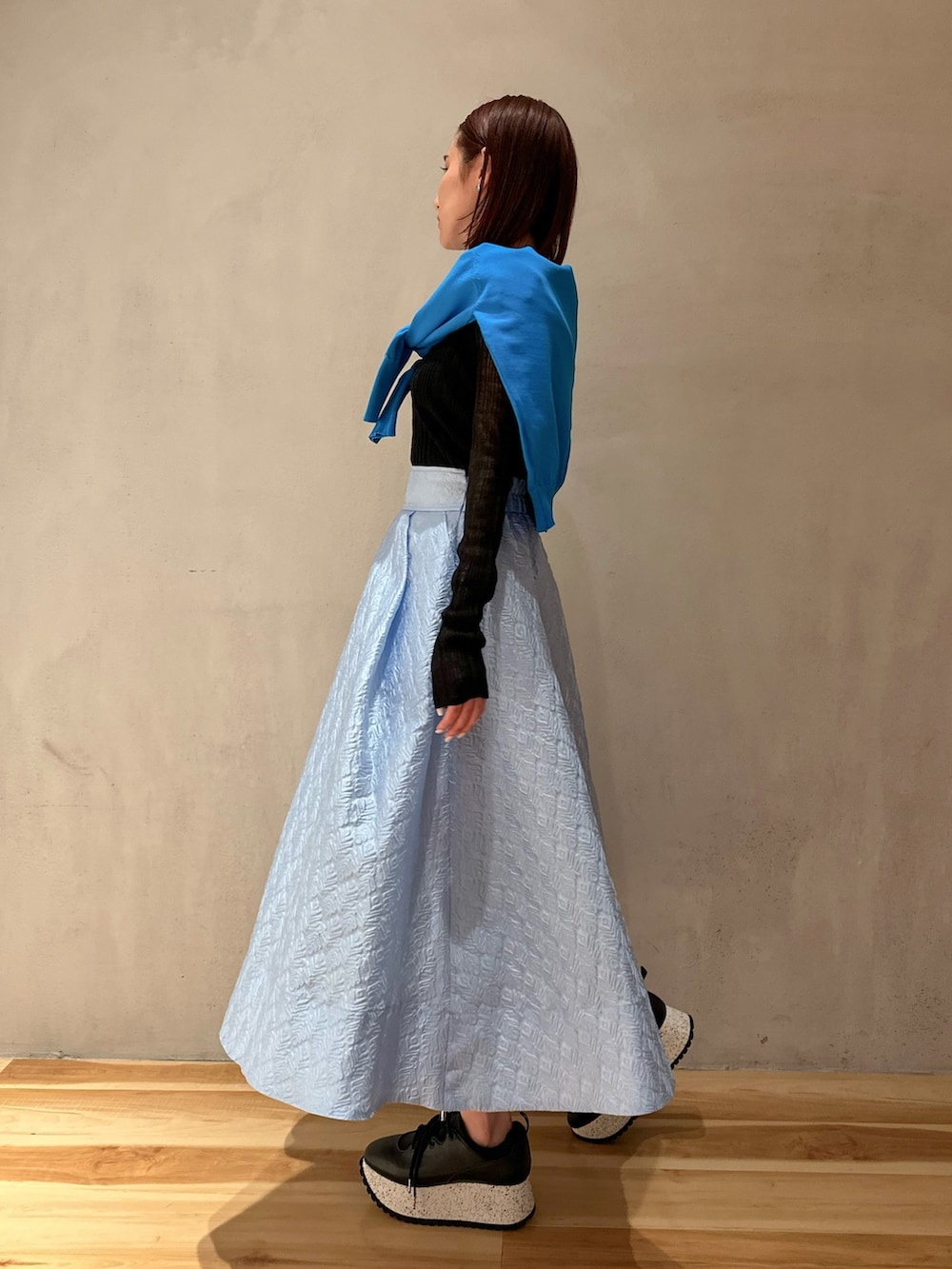 ブルー系のスカート、ブラック系のスニーカー、ブルー系のカーディガン/ボレロを着用したレディースの春コーディネートの2枚目の写真