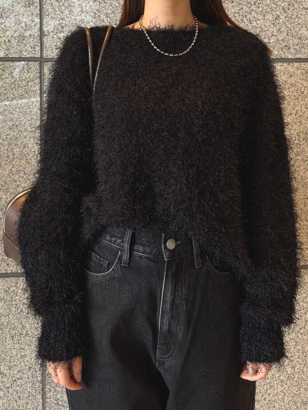 ブラック系のニット/セーター、ブラック系のデニムパンツ、ブラウン系のボストンバッグを着用したレディースの冬コーディネートの5枚目の写真