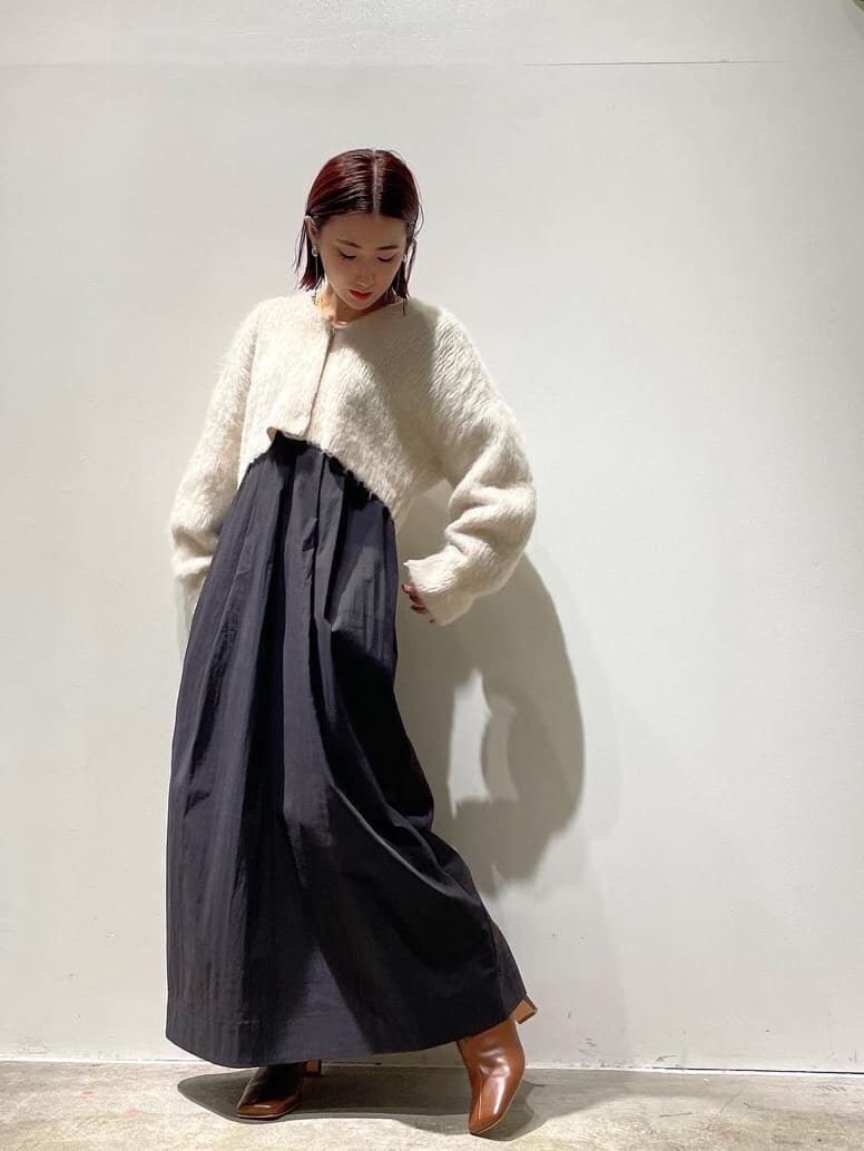 ブラック系のダウンジャケット/コート、ブラウン系のブーツ、ホワイト系のワンピースを着用したレディースの秋コーディネートの4枚目の写真