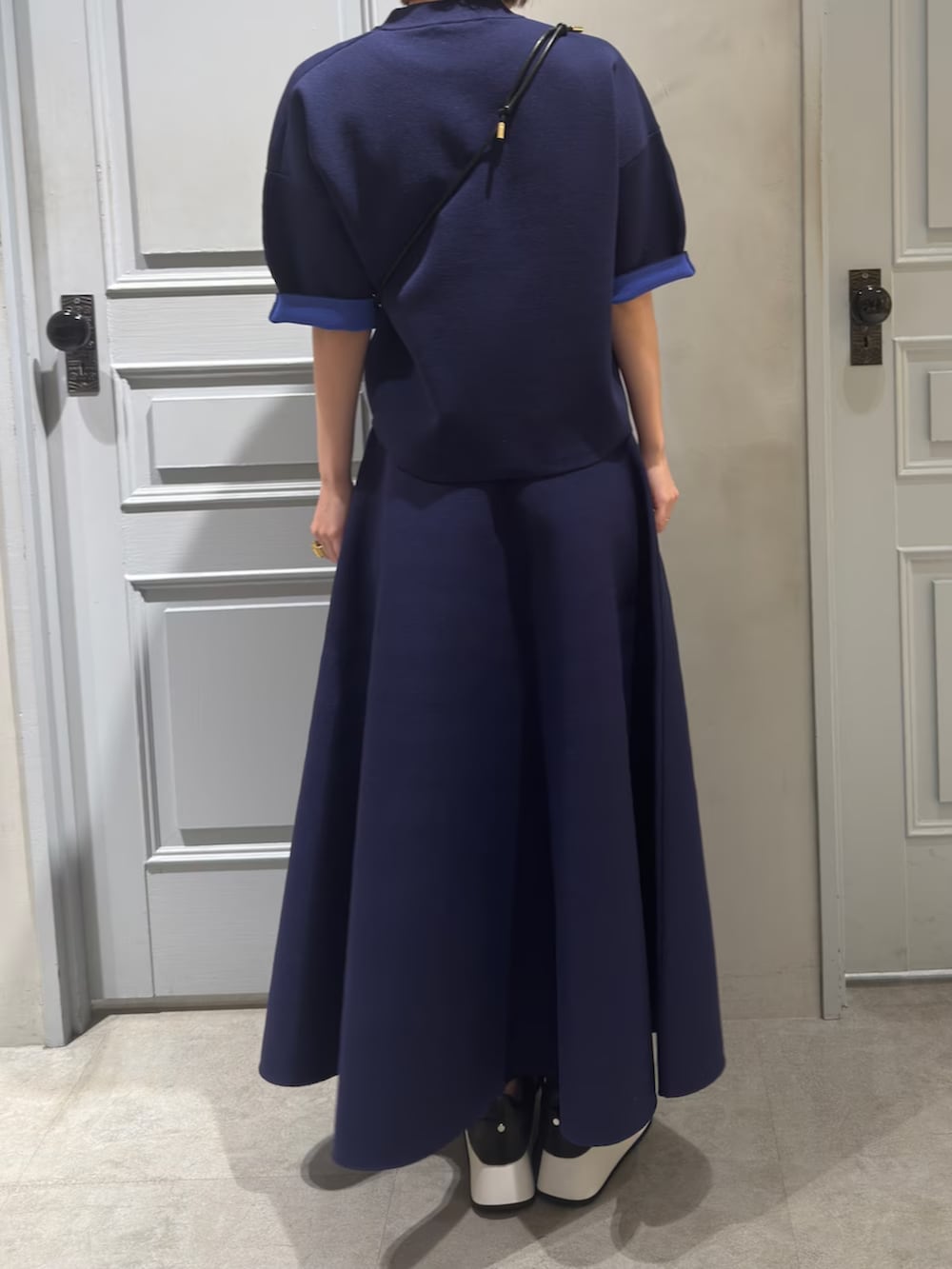 ブルー系のニット/セーター、ブルー系のスカート、ブラック系のスマホグッズを着用したレディースの春コーディネートの4枚目の写真