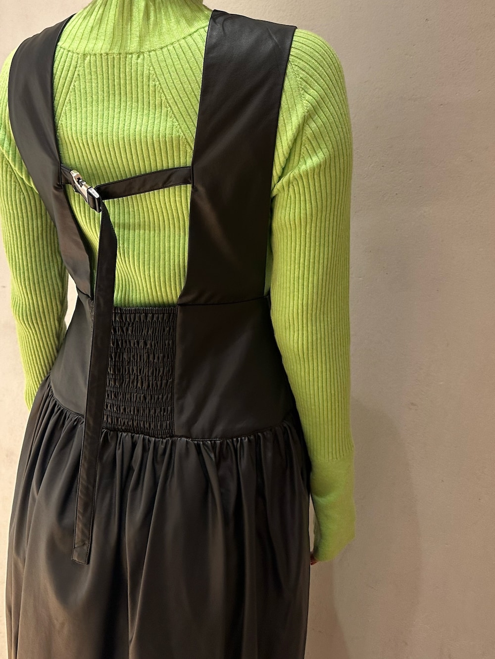 ブラック系のジャンパースカート、ブラック系のブーツ、グリーン系のニット/セーターを着用したレディースの秋コーディネートの6枚目の写真