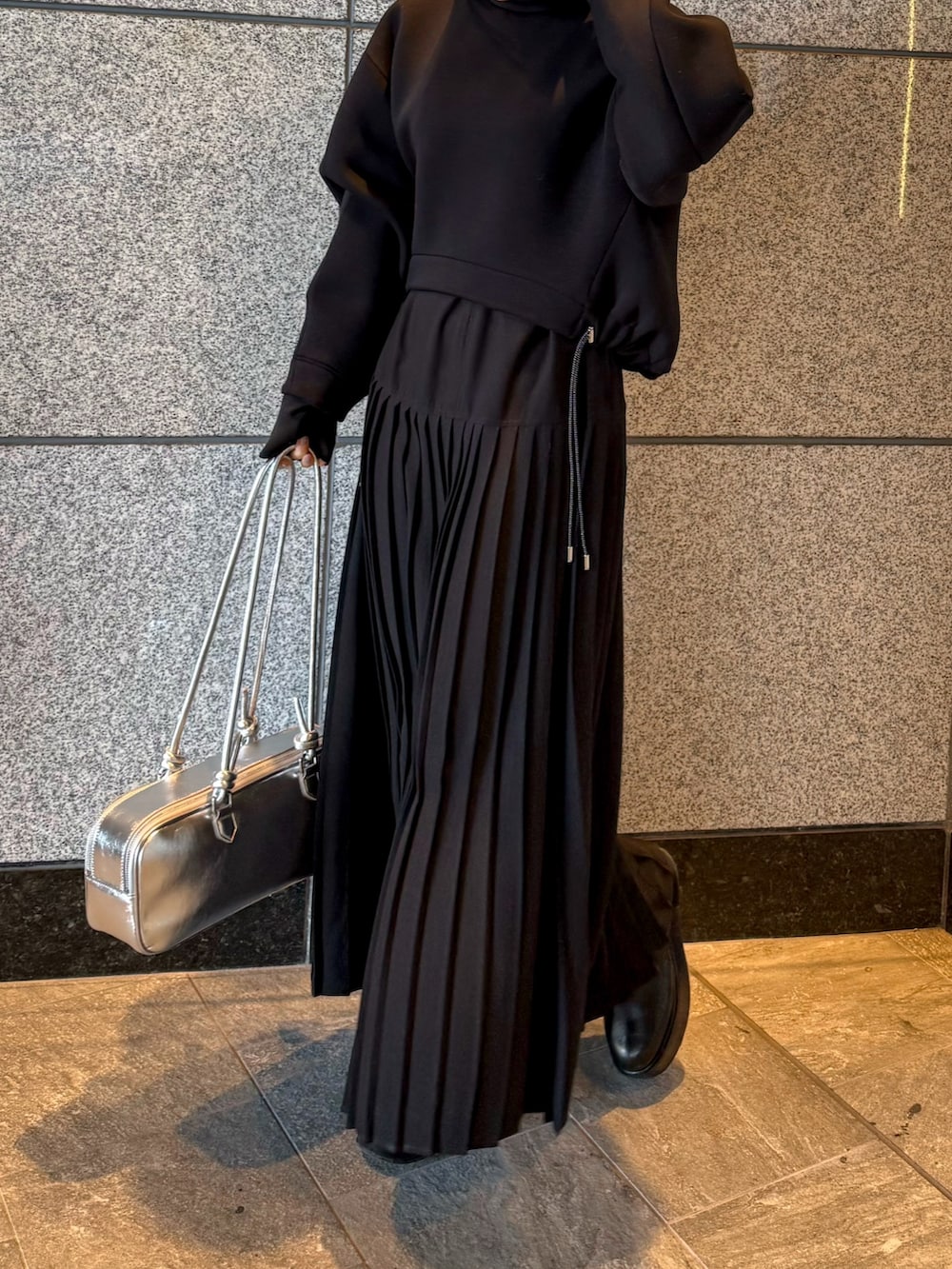 ブラック系のスウェット、シルバー系のボストンバッグ、ブラック系のワンピースを着用したレディースの冬コーディネートの5枚目の写真