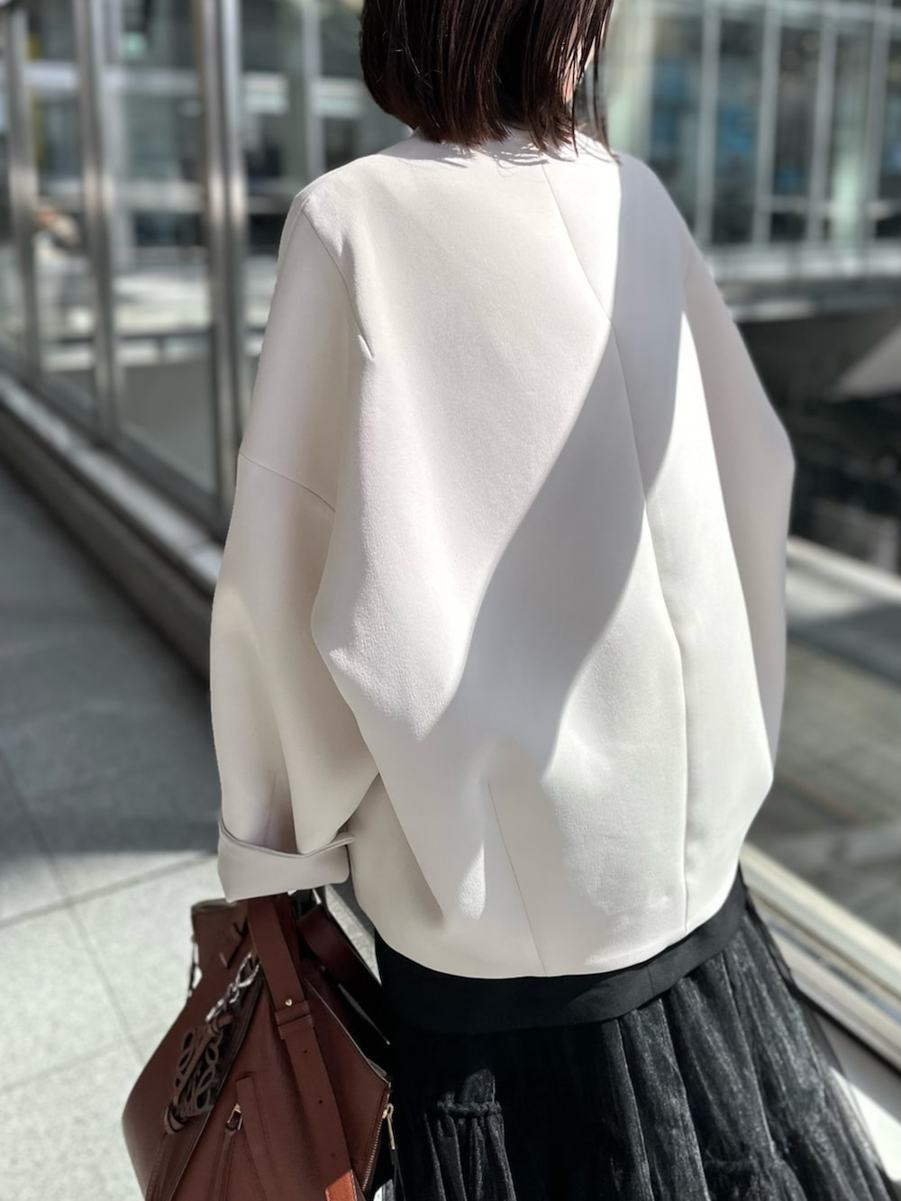 シルバー系のパンプス、ブラック系のスカート、ベージュ系のノーカラーコートを着用したレディースの春コーディネートの6枚目の写真