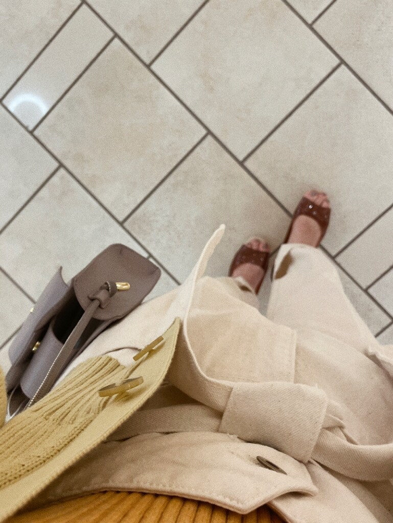 ホワイト系のデニムパンツ、ブラウン系のパンプス、パープル系のハンドバッグを着用したレディースの冬コーディネートの5枚目の写真