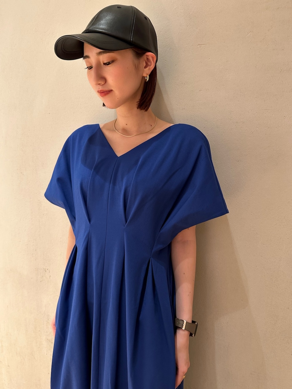 ブルー系のワンピース、ホワイト系のスニーカー、ブラック系のキャップを着用したレディースの春コーディネートの8枚目の写真