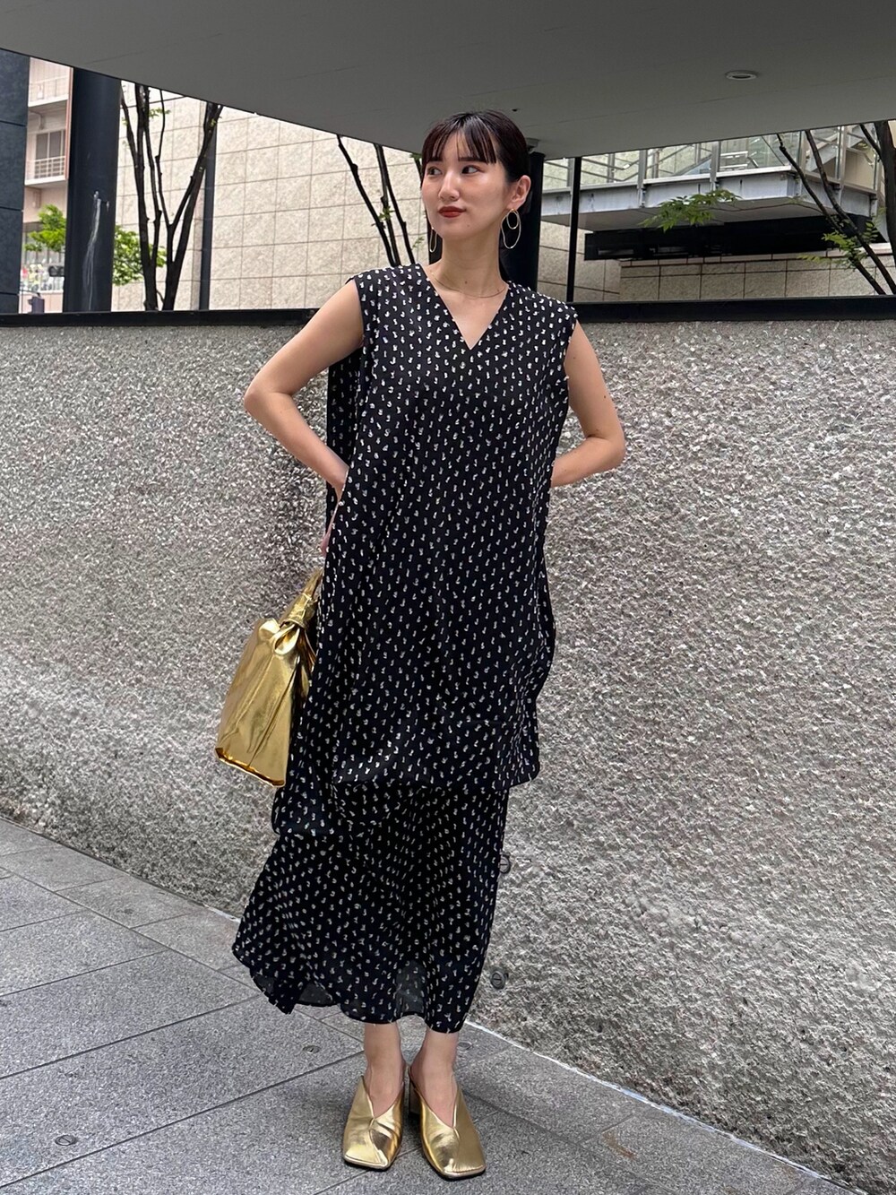 ブラック系のワンピース、ゴールド系のハンドバッグ、ゴールド系のパンプスを着用したレディースの夏コーディネートの3枚目の写真