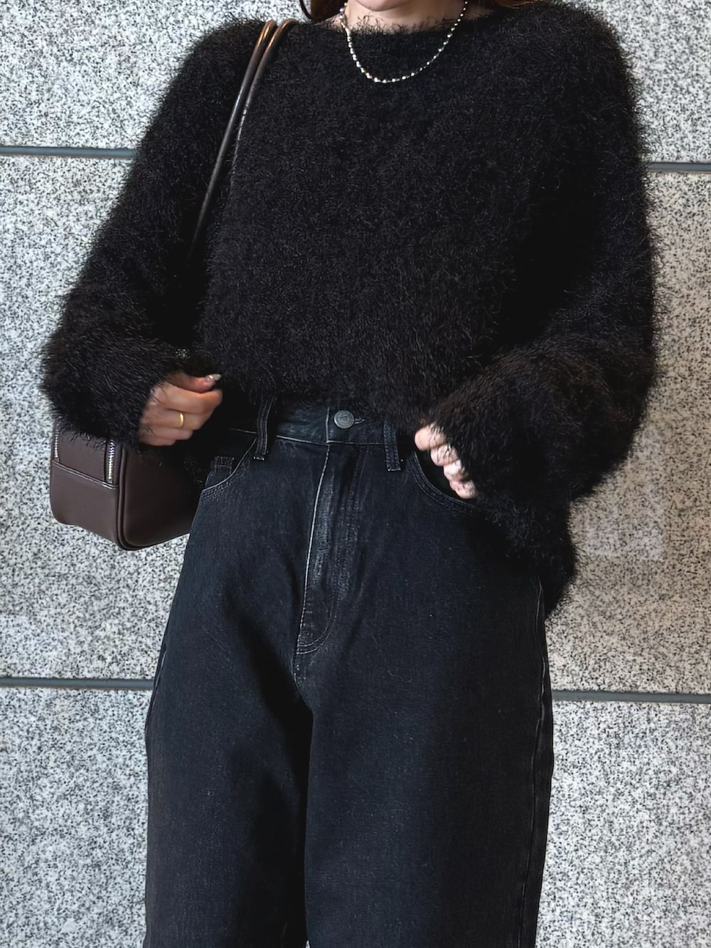 ブラック系のニット/セーター、ブラック系のデニムパンツ、ブラウン系のボストンバッグを着用したレディースの冬コーディネートの10枚目の写真