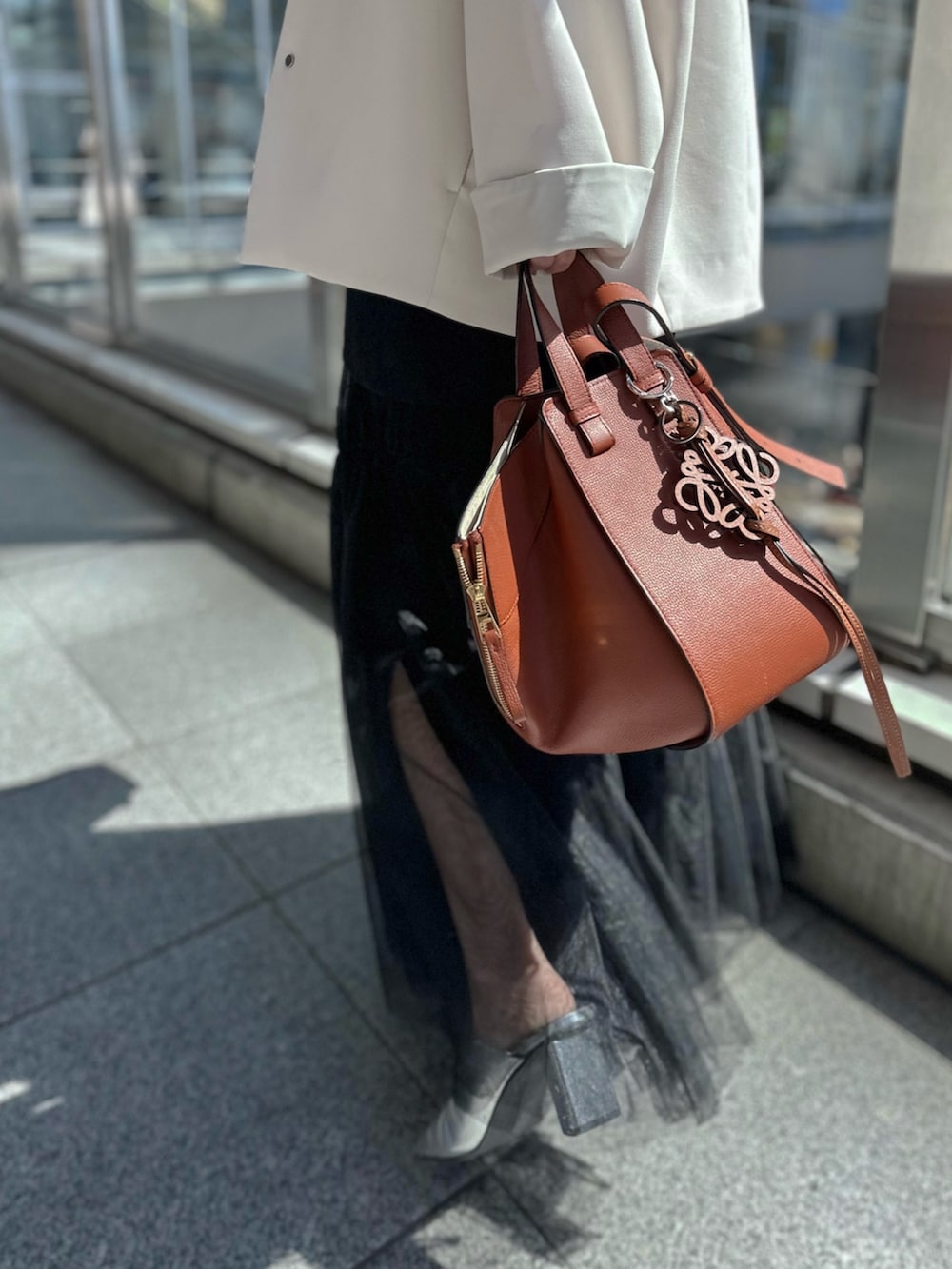 シルバー系のパンプス、ブラック系のスカート、ベージュ系のノーカラーコートを着用したレディースの春コーディネートの8枚目の写真