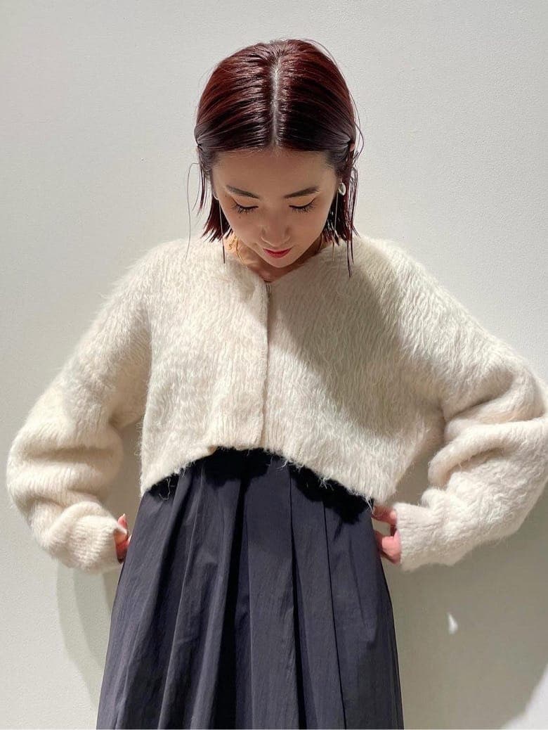 ブラック系のダウンジャケット/コート、ブラウン系のブーツ、ホワイト系のワンピースを着用したレディースの秋コーディネートの2枚目の写真