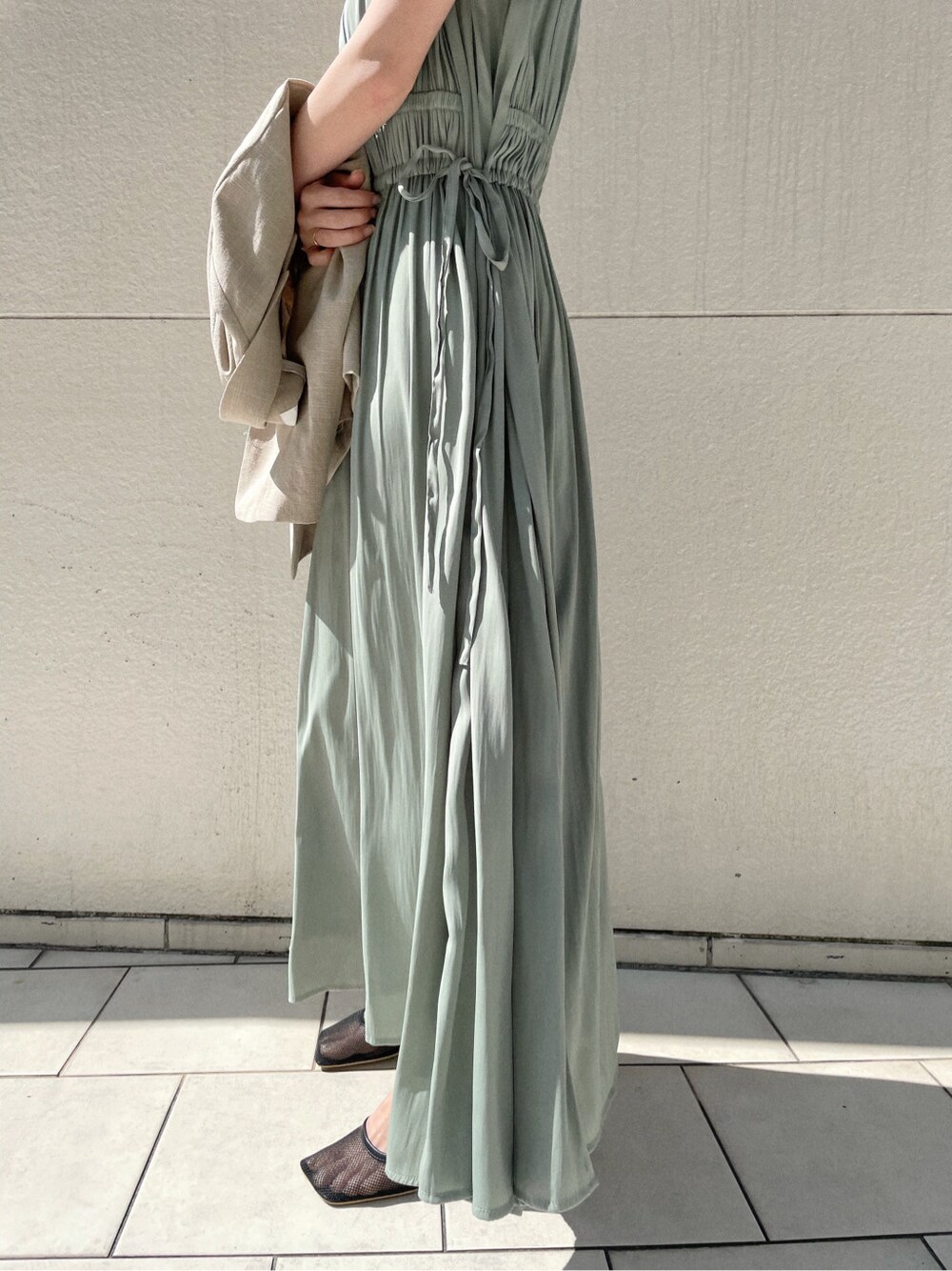 ブラック系のサンダル、ベージュ系のテーラードジャケット、グリーン系のワンピースを着用したレディースの春コーディネートの2枚目の写真