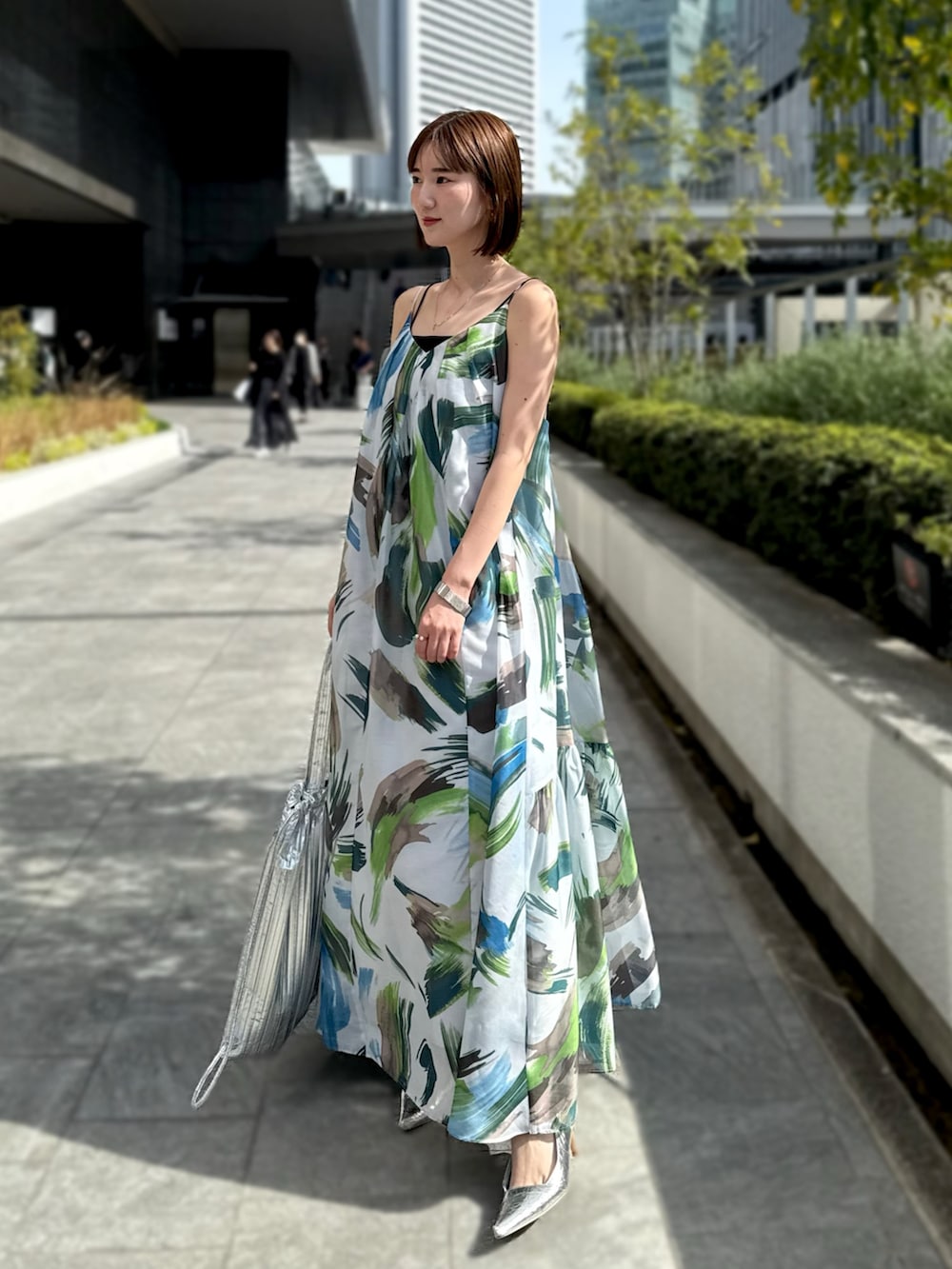 グリーン系のワンピース、シルバー系のトートバッグ、シルバー系のサンダルを着用したレディースの春コーディネートの2枚目の写真