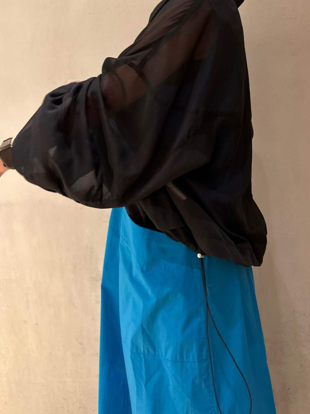 ブルー系のワンピース、ホワイト系のサンダル、ブラック系のブルゾンを着用したレディースの冬コーディネートの7枚目の写真