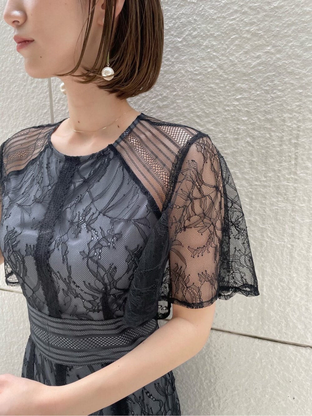 ゴールド系のパンプス、ゴールド系のクラッチバッグ、ブラック系のドレスを着用したレディースの春コーディネートの4枚目の写真
