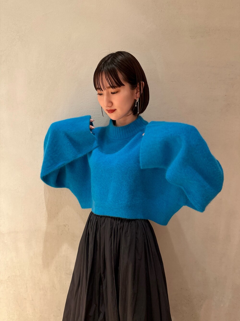 ブラック系のスカート、ブルー系のニット/セーター、ホワイト系のブーツを着用したレディースの冬コーディネートの5枚目の写真