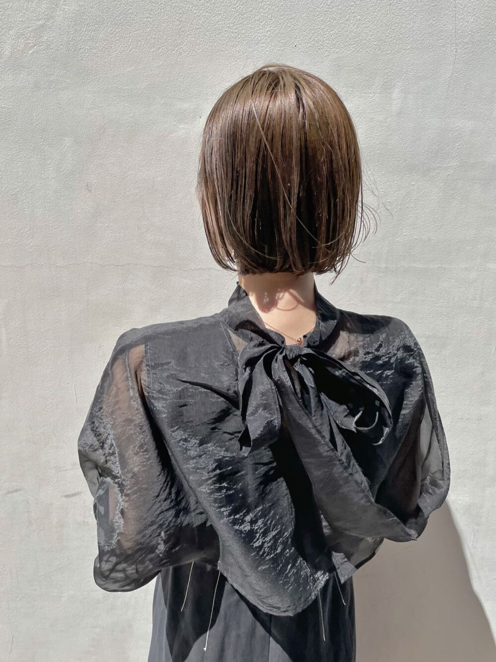 ブラウン系のパンプス、ブラック系のワンピース、ゴールド系のブレスレットを着用したレディースの春コーディネートの4枚目の写真