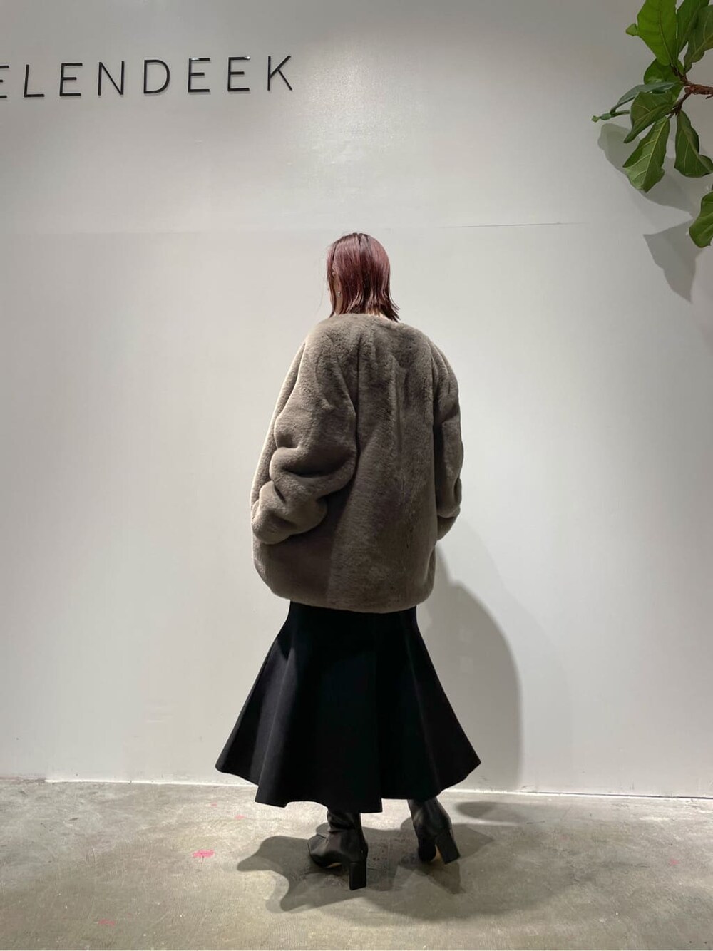 ブラウン系のノーカラーコート、ベージュ系のニット/セーター、ブラック系のブーツを着用したレディースの秋コーディネートの5枚目の写真