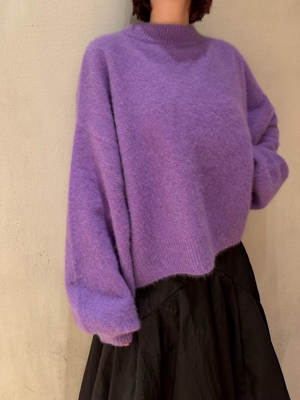 ブラック系のスカート、パープル系のニット/セーター、ブラック系のブーツを着用したレディースの秋コーディネートの6枚目の写真